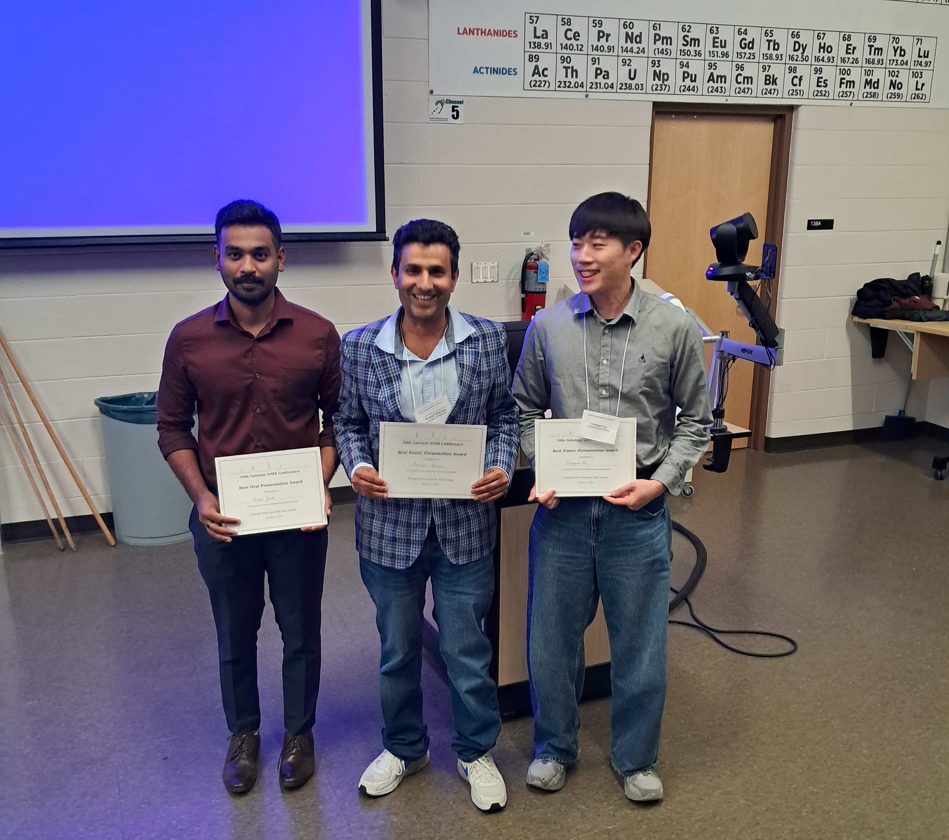 Three people holding certificates at an awards ceremony